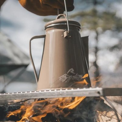 Kakikleurige geëmailleerde ketel van Robens met beugel om aan een haak boven het vuur te hangen.